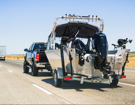 A semi-truck towing a large boat along the interstate, used for reliable long-distance boat transport in the U.S.