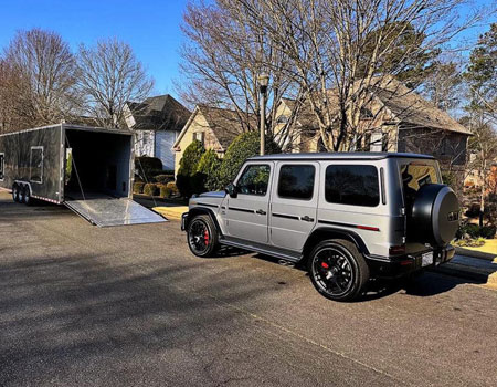 Mercedes G-Class being loaded into a sleek enclosed trailer in an urban area, providing door-to-door enclosed auto transport service