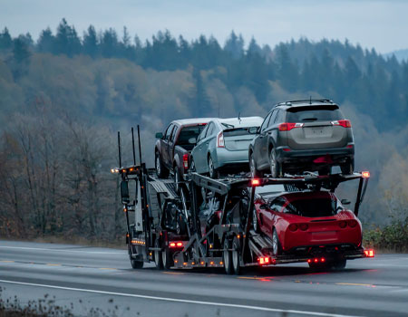 Fully loaded open car carrier truck on the highway, providing open car shipping service across the U.S.