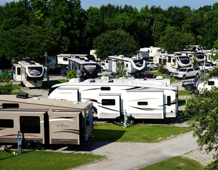 Dozens of towable RVs parked at a campsite in a lush green area